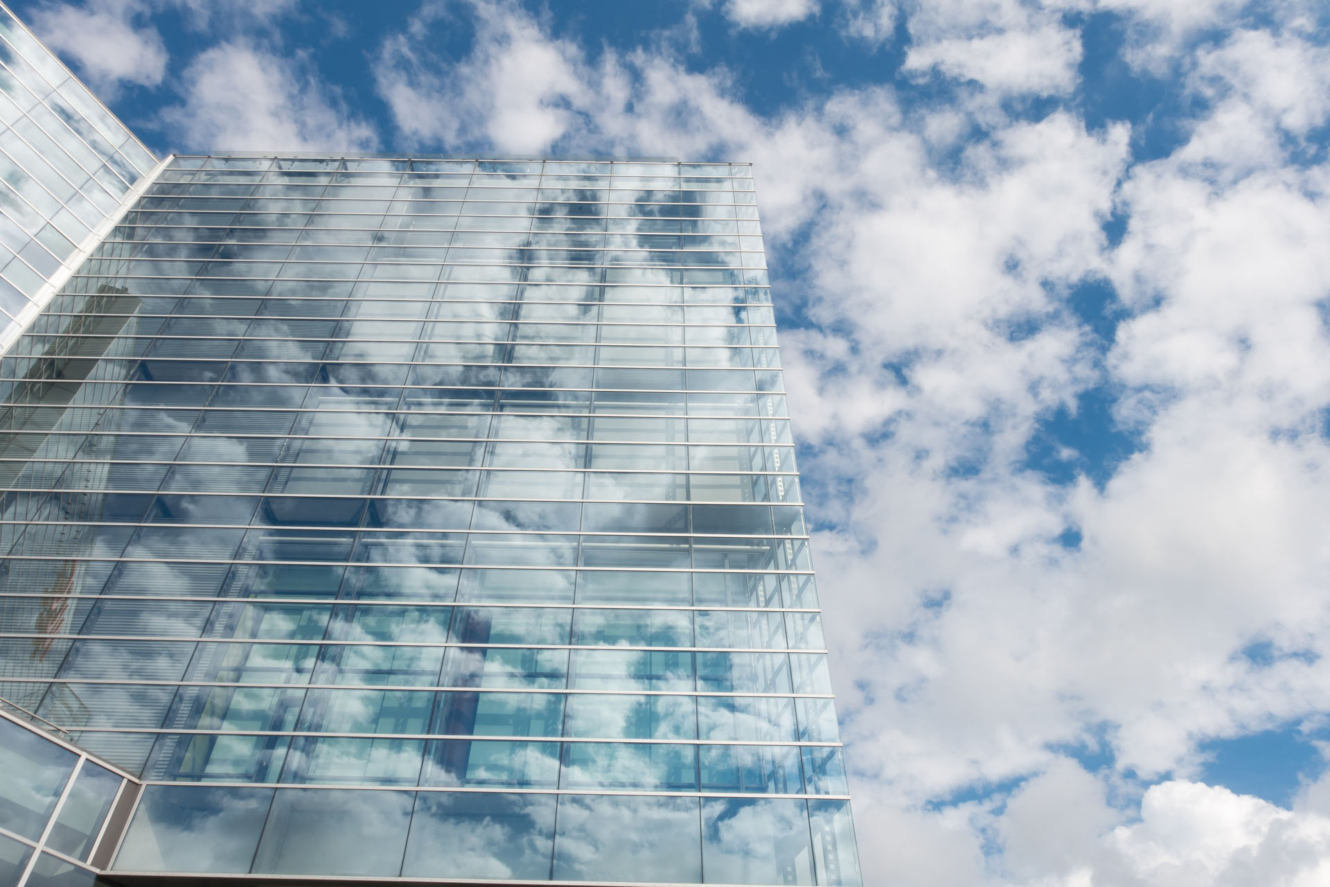 Photo of clouds on tall mirror office building.